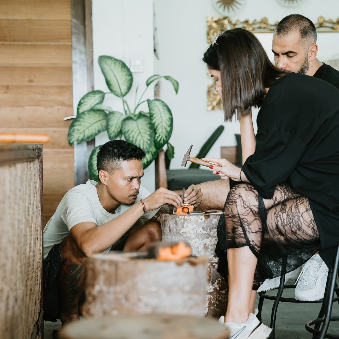 Couple hammering silver with a master silversmith during a class