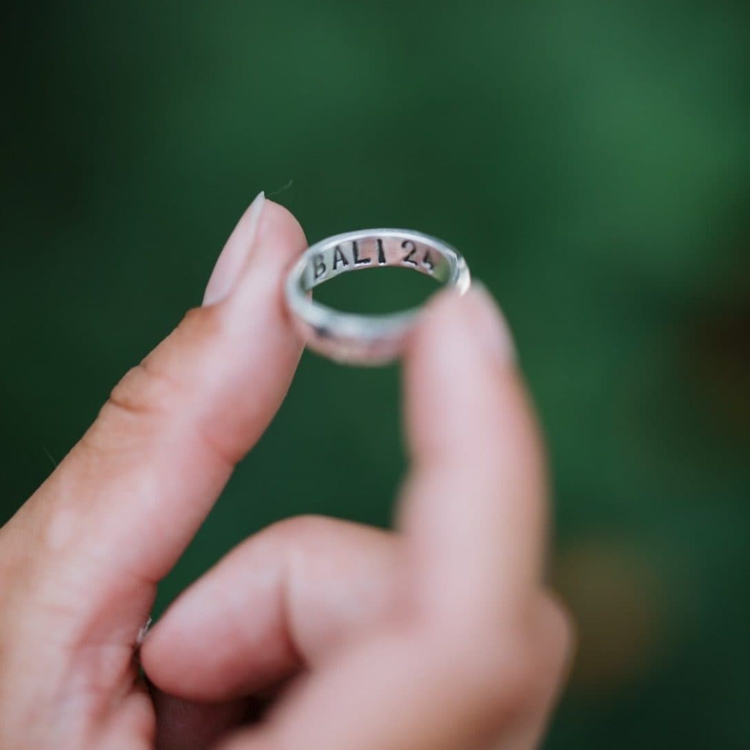 A finished silver ring engraved BALI 24, held up by its maker